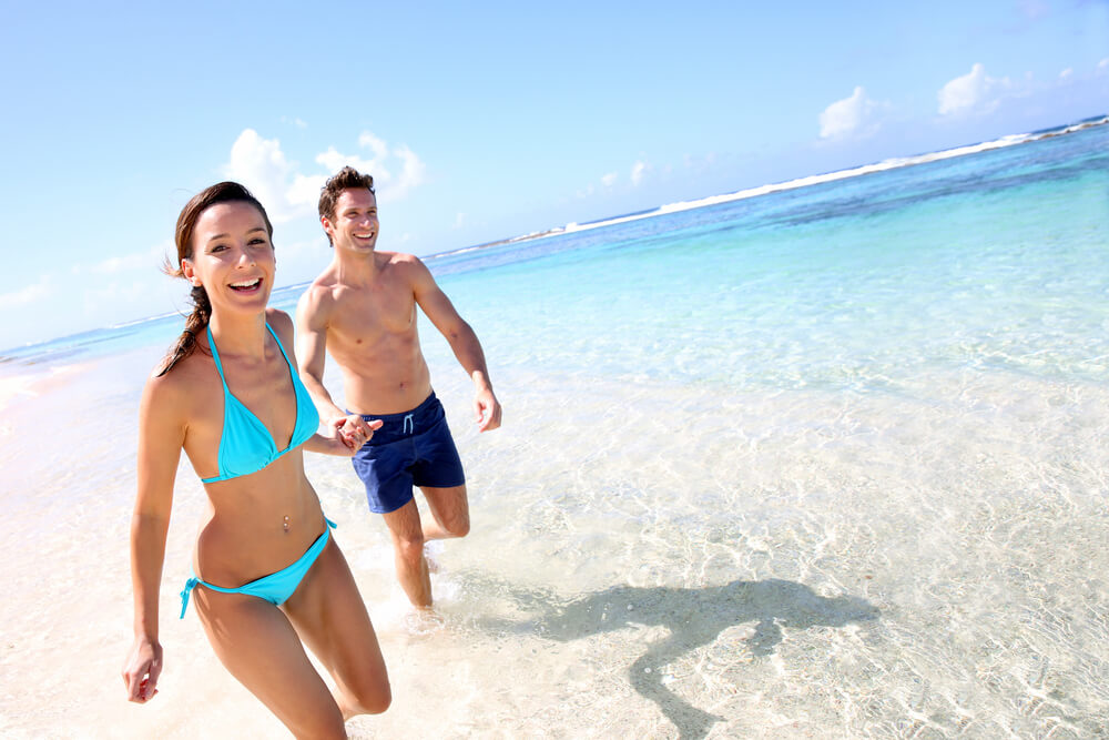 A couple running on one of the best beaches in Nassau Bahamas.