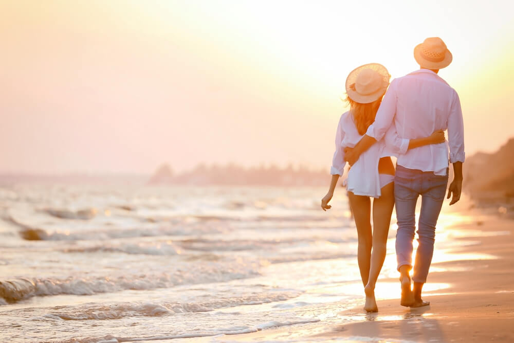 A couple walking on the beach while on their honeymoon in the Bahamas.