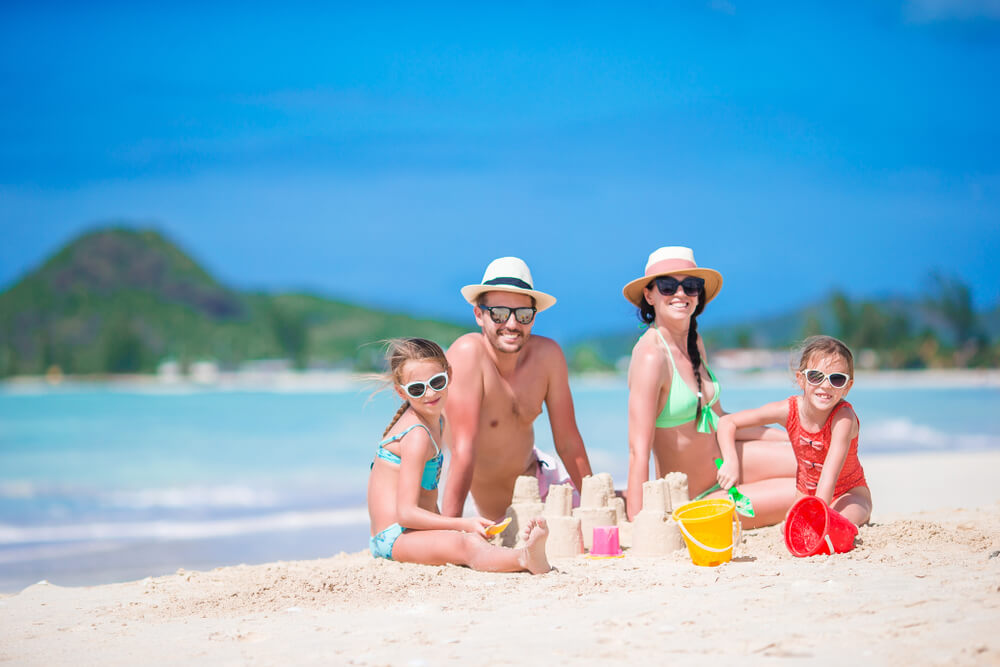 A family building sand castles on the beach, one of the best things to do in the Bahamas with kids.